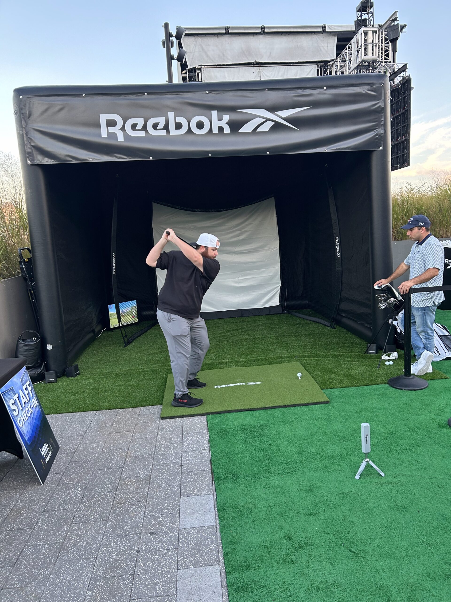 Golfer swinging in Reebok-branded portable golf simulator