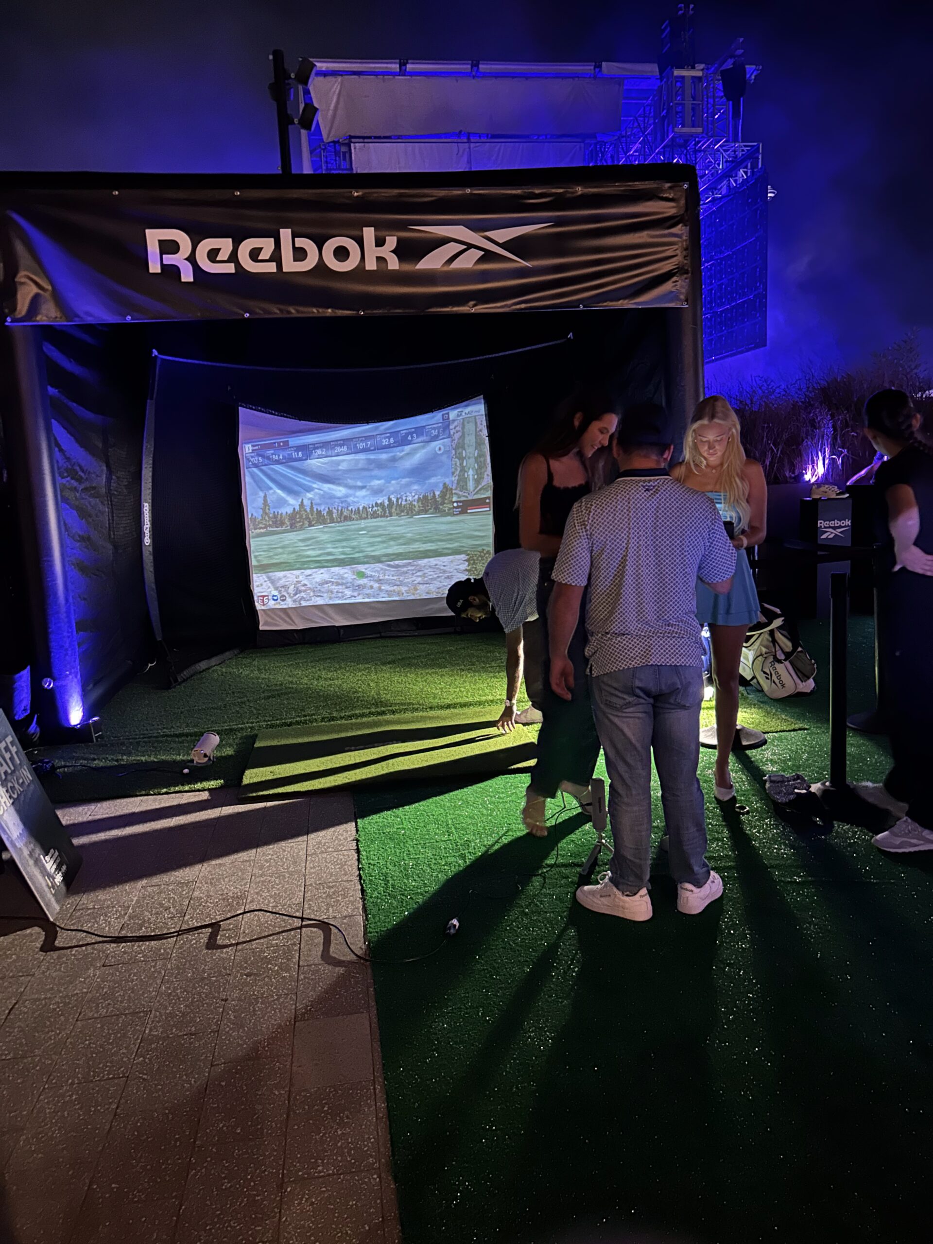 Reebok-branded golf simulator setup with players