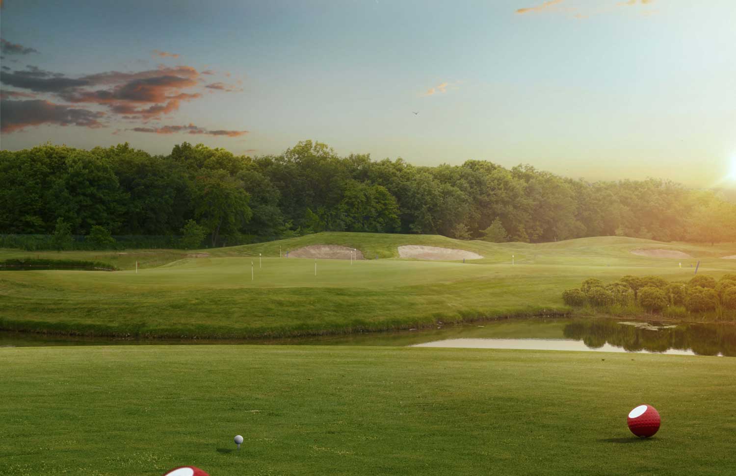 Golf course landscape at sunset with golf balls on the green, highlighting the serene environment for indoor golf practice at ParTee Golf.