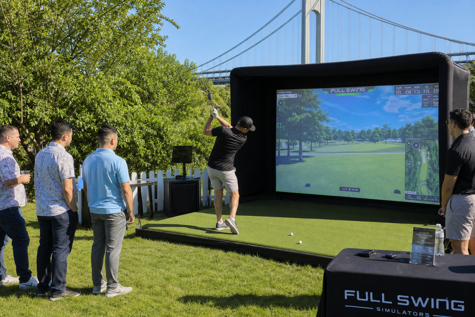 Golfer swinging club in front of portable golf simulator screen displaying a virtual course, with spectators watching in a grassy outdoor setting in Staten Island.